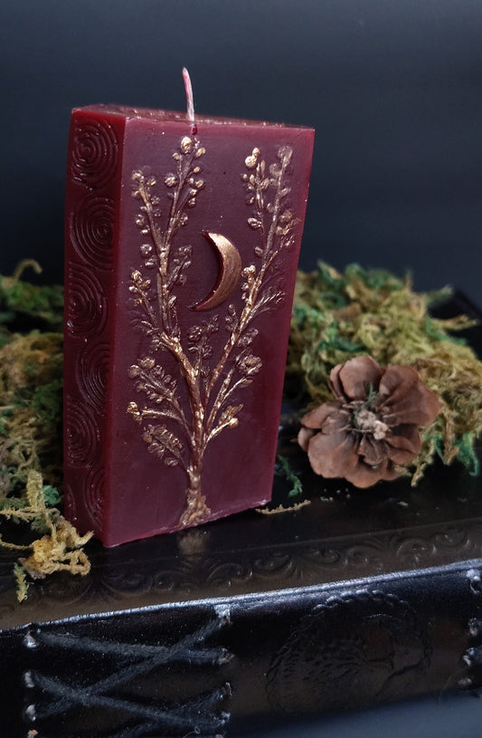 Sculptural candle with three apple tree carvings and a Triskele symbol, bronze‑detailed, handmade in Sioux Falls, SD.