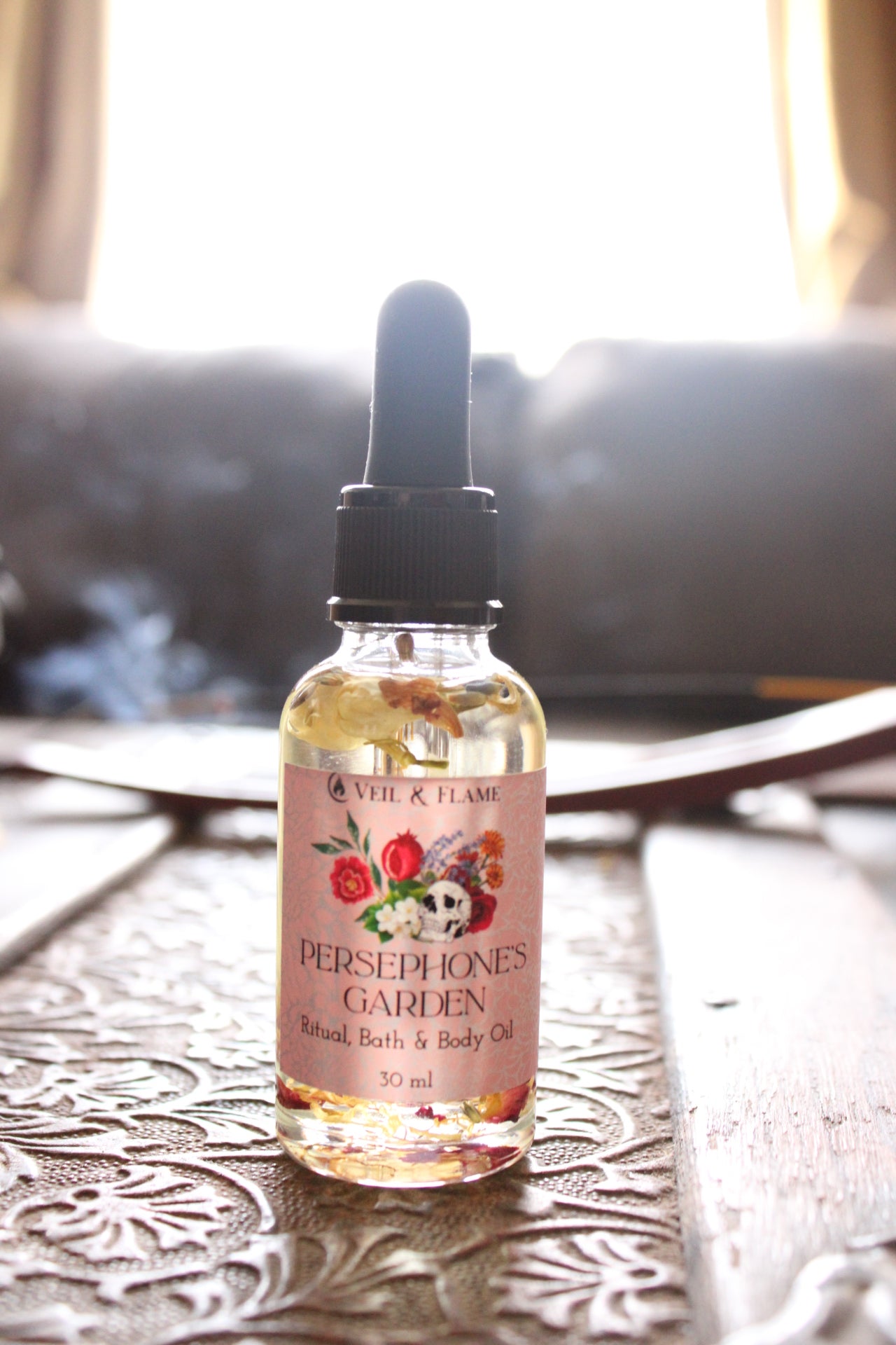Bottle of Persephones Garden bath and body oil on a textured surface