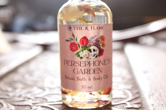 Bottle of 'Persephone's Garden' bath and body oil with floral label on a wooden surface.