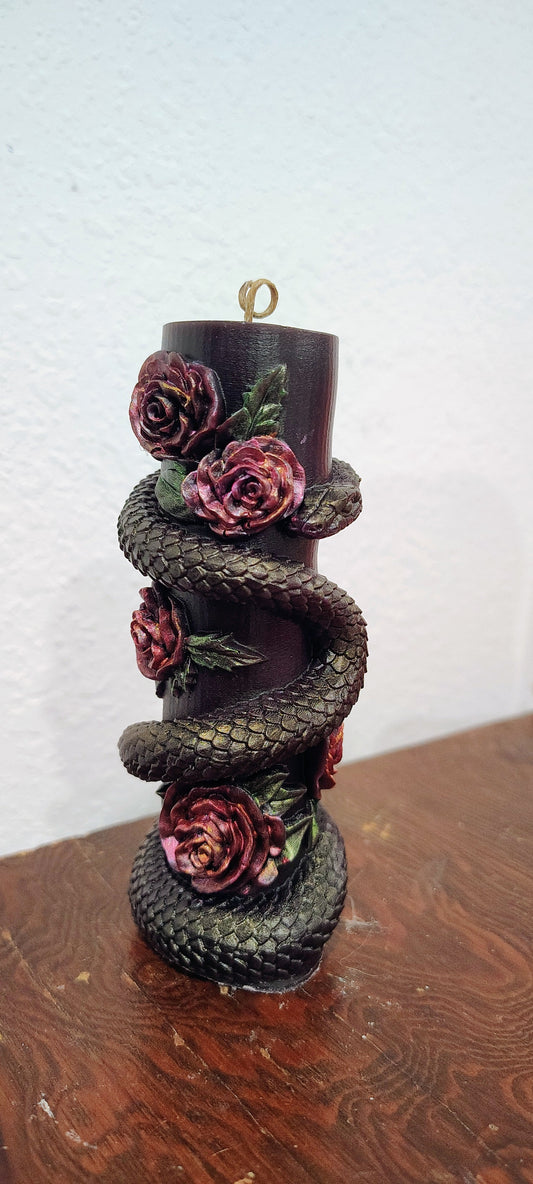 candle featuring a snake and roses motif