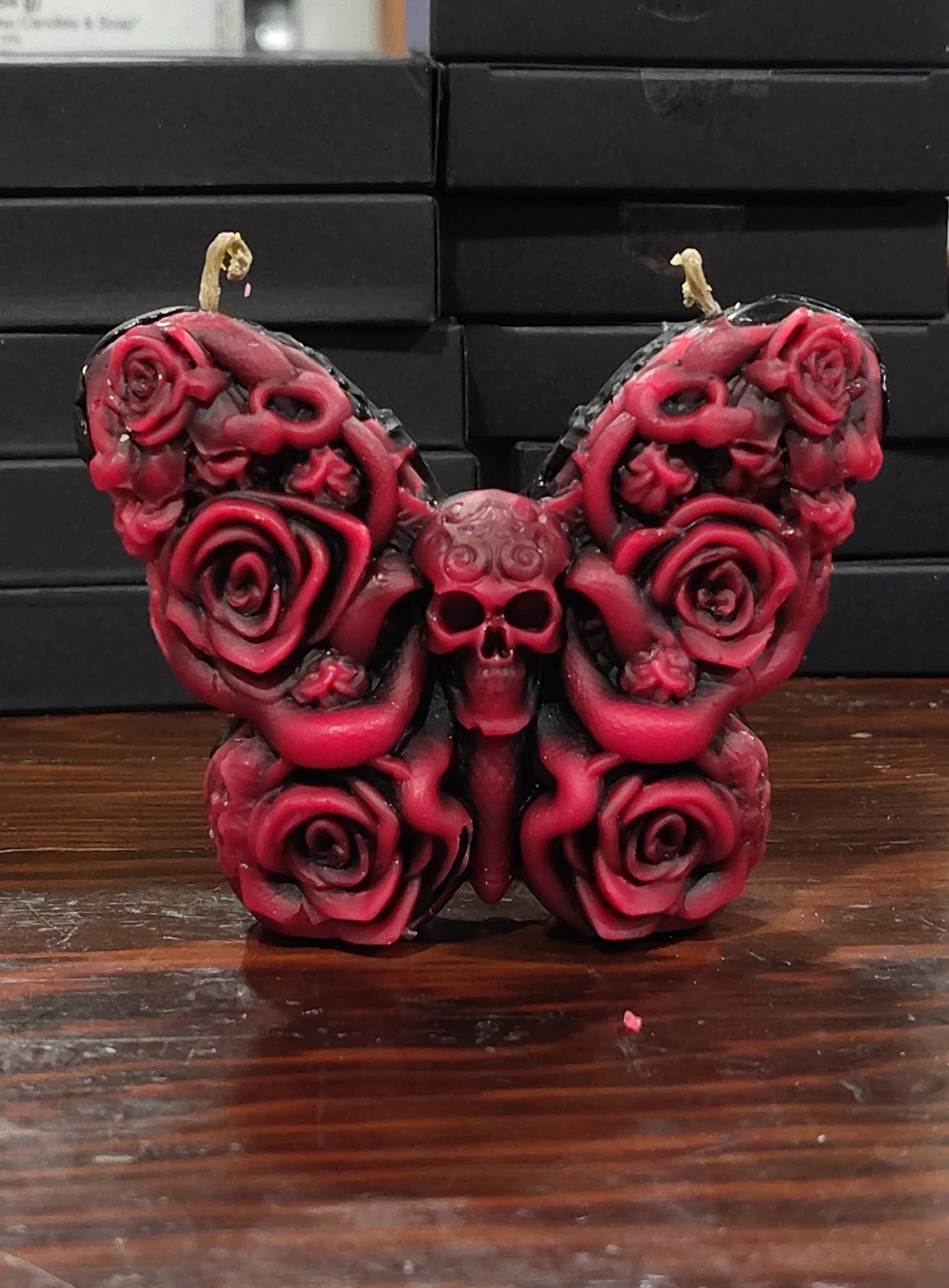 Skull butterfly candle with dual wicks and carved rose‑wing details, handmade in Sioux Falls, SD.