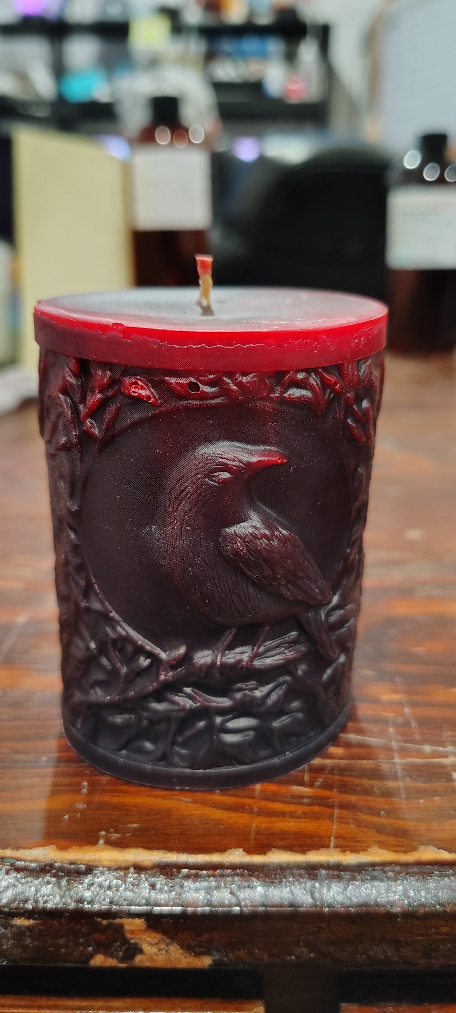 Black crow pillar candle with carved double‑sided crow design and customizable accent color, handmade in Sioux Falls, SD.