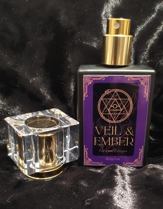 Perfume bottle labeled 'Veil & Ember' next to a clear glass container on a dark textured background