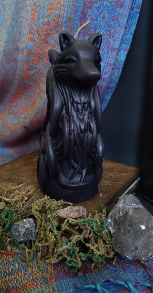 Black two headed wolf candle on a textured surface with crystals and stones