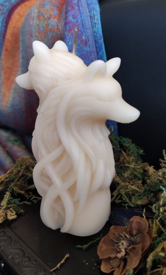 White wolf-shaped candle on a textured surface with a colorful fabric background