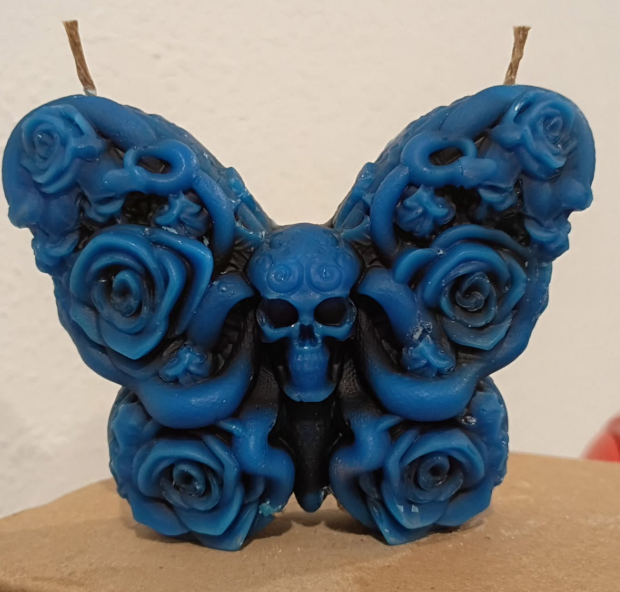 Skull butterfly candle with dual wicks and carved rose‑wing details, handmade in Sioux Falls, SD.