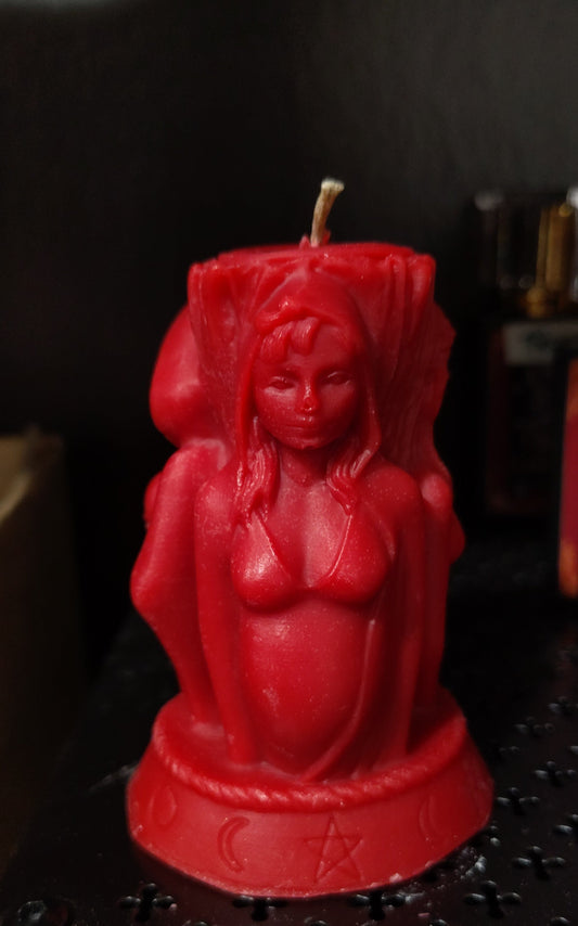 Red candle shaped like a deity figure on a dark surface