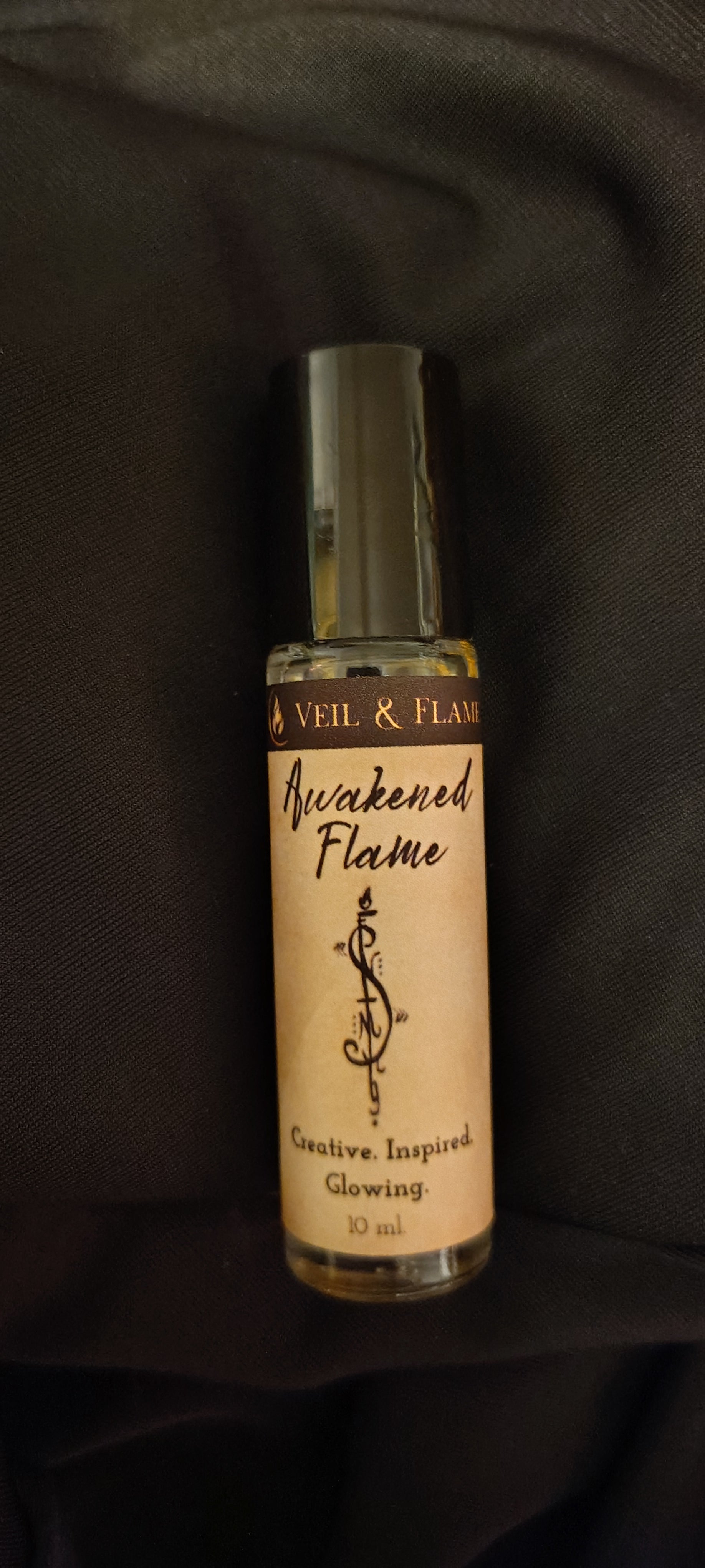 Awakened Flame ritual oil with calendula petals and rutilated quartz in a 10 ml roller bottle, handmade in Sioux Falls, SD.