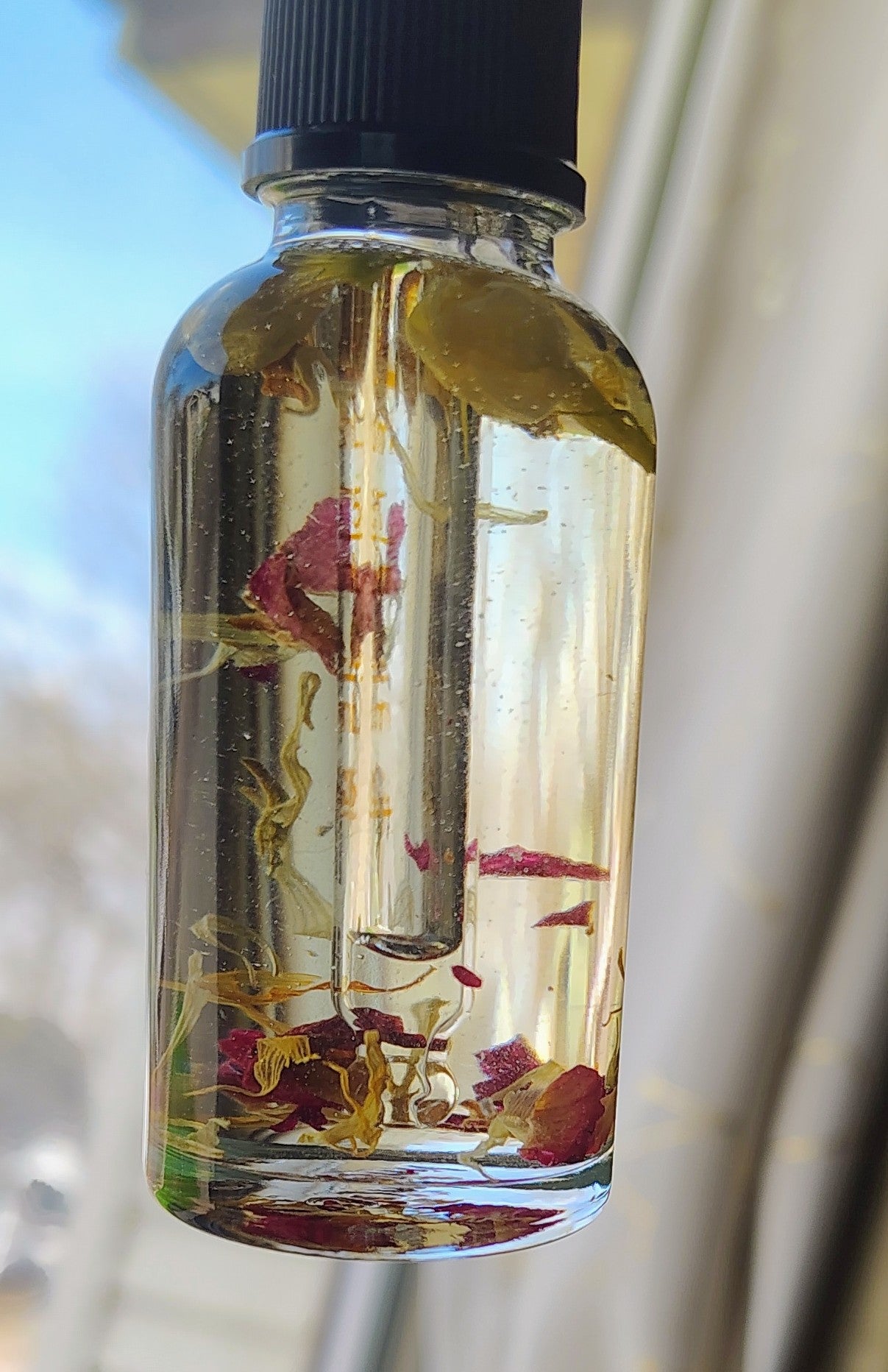 Glass bottle with floral elements and a black cap on a blurred background