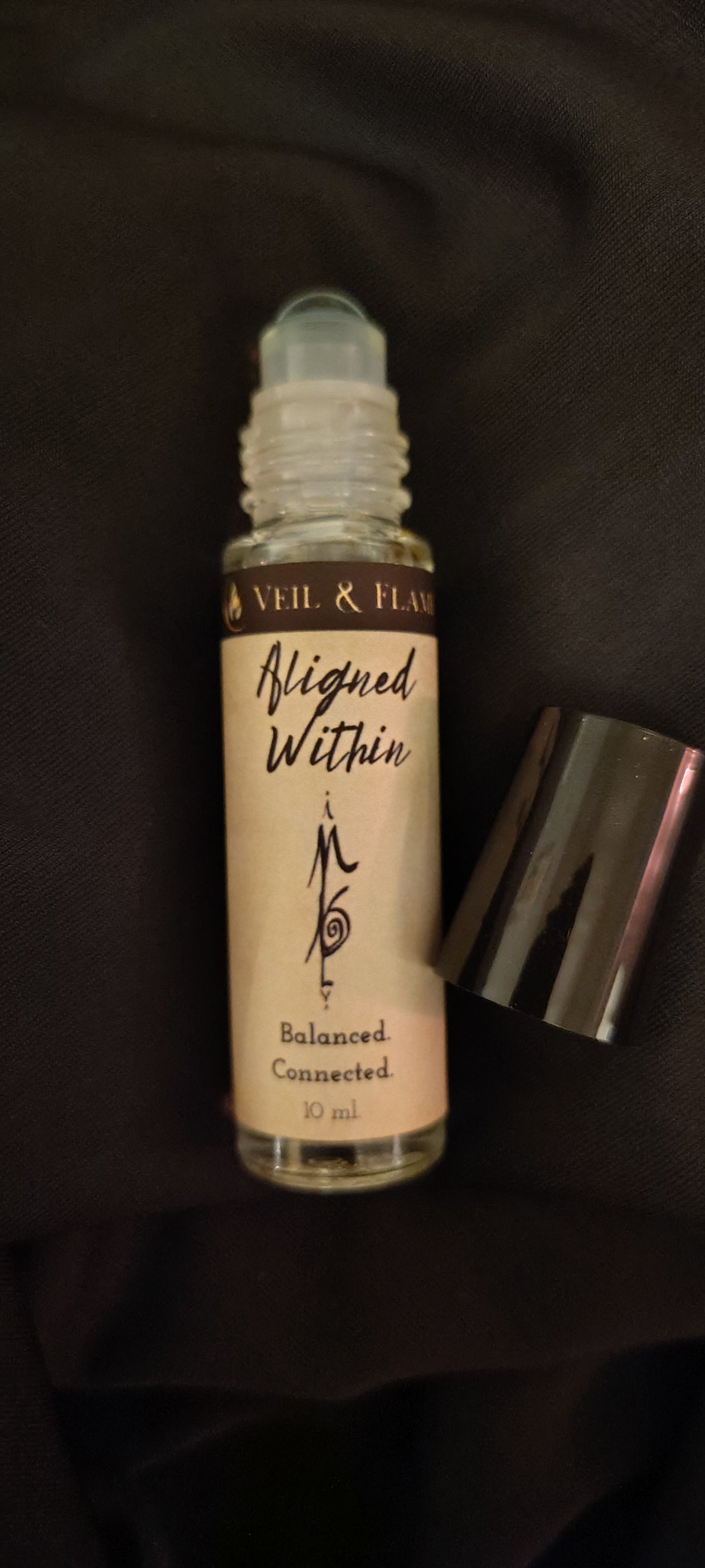 Aligned Within ritual oil with amethyst chips and jasmine buds in a 10 ml roller bottle, handmade in Sioux Falls, SD.