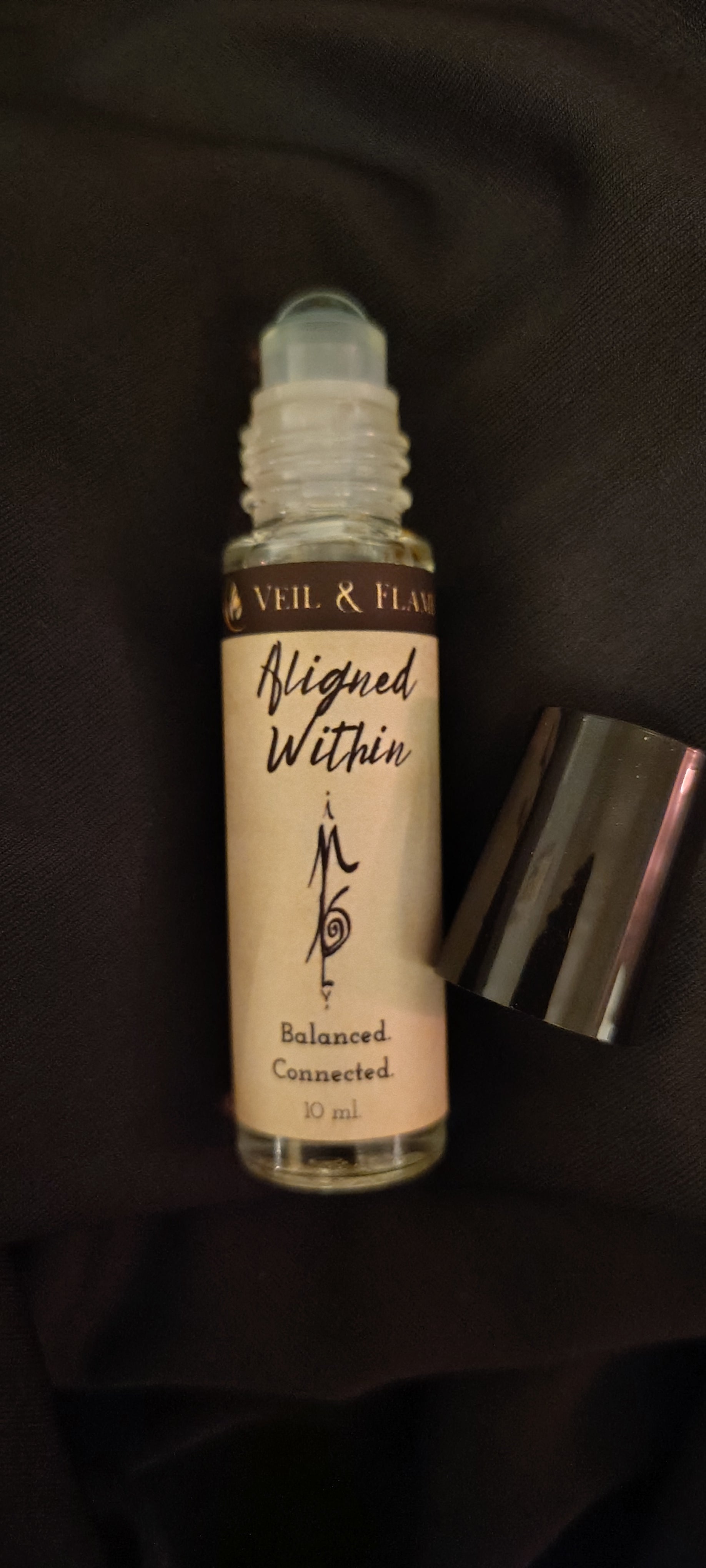 Aligned Within ritual oil with amethyst chips and jasmine buds in a 10 ml roller bottle, handmade in Sioux Falls, SD.
