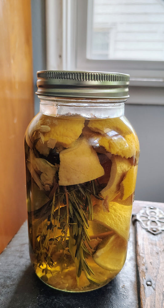 Mason jar with botanicals and citrus on a wooden surface