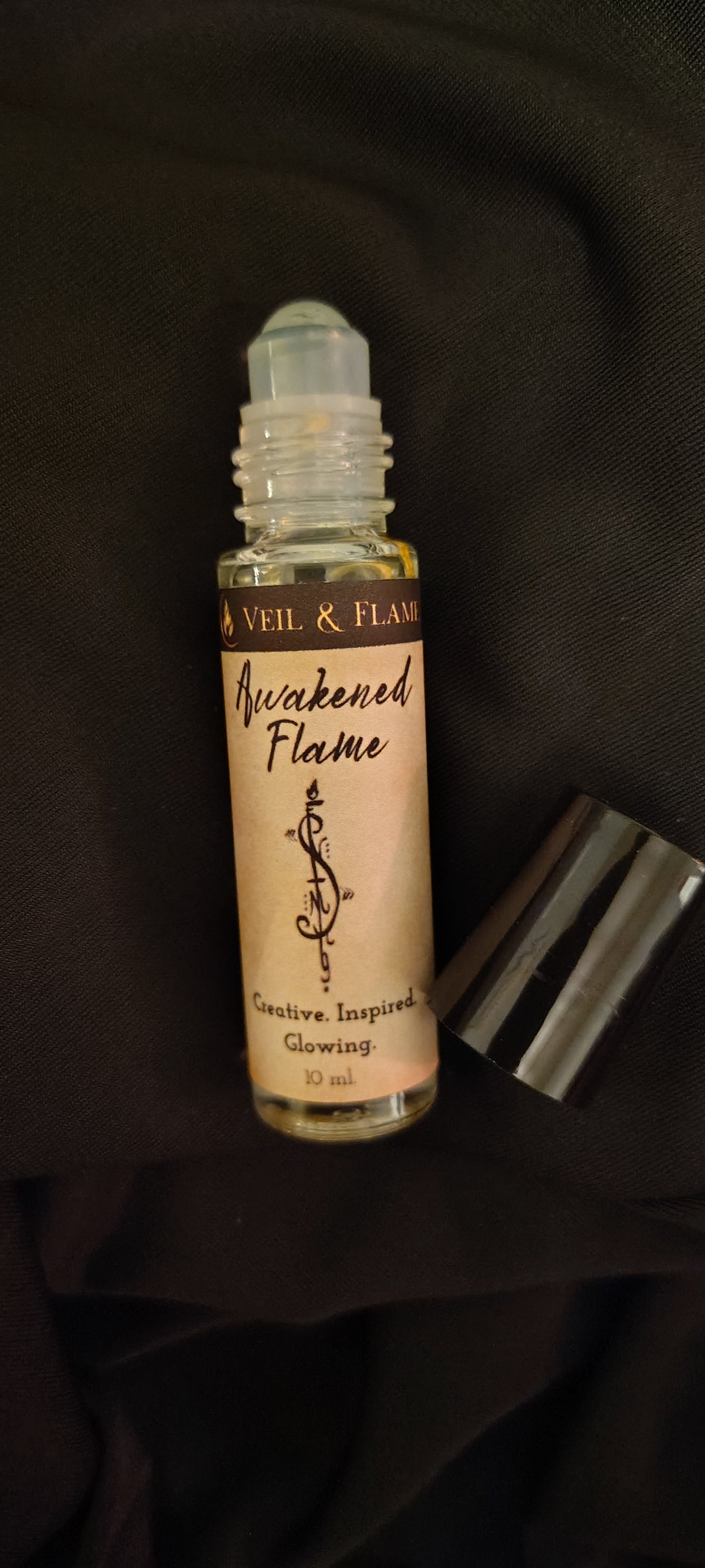 Awakened Flame ritual oil with calendula petals and rutilated quartz in a 10 ml roller bottle, handmade in Sioux Falls, SD.