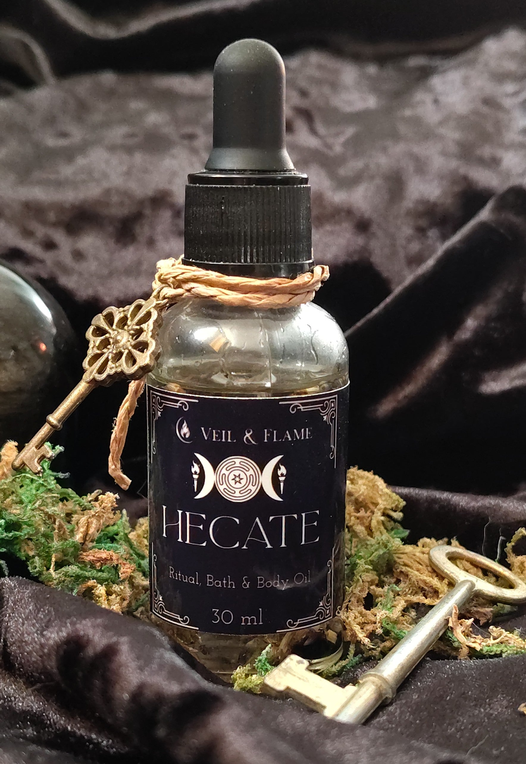 Hecate ritual oil with obsidian and moonstone chips in a 1 oz dropper bottle, handmade in Sioux Falls, SD.