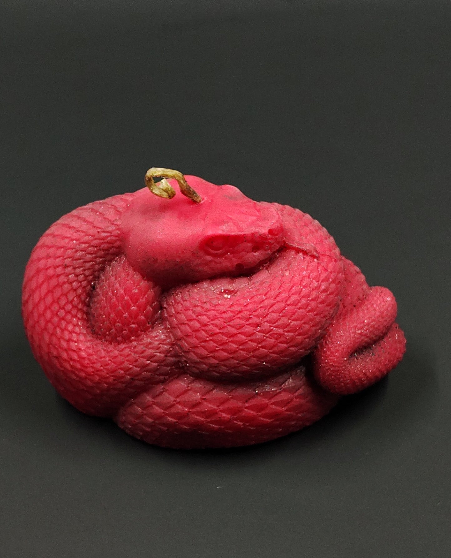 Red snake-shaped candle on a black background