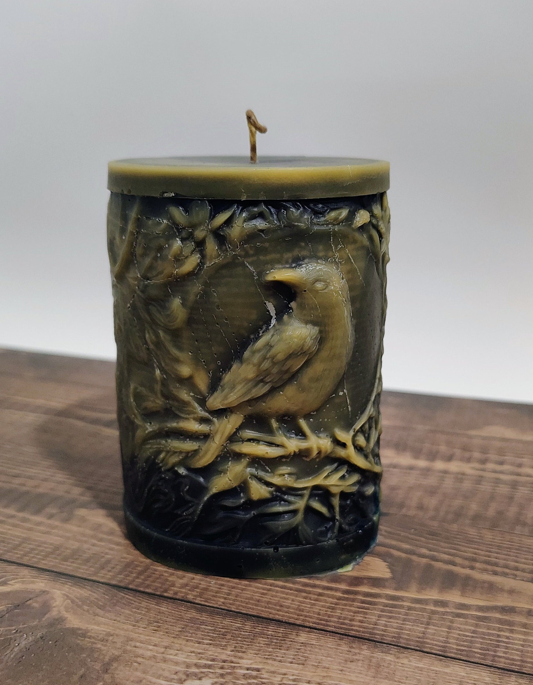 Black crow pillar candle with carved double‑sided crow design and customizable accent color, handmade in Sioux Falls, SD.