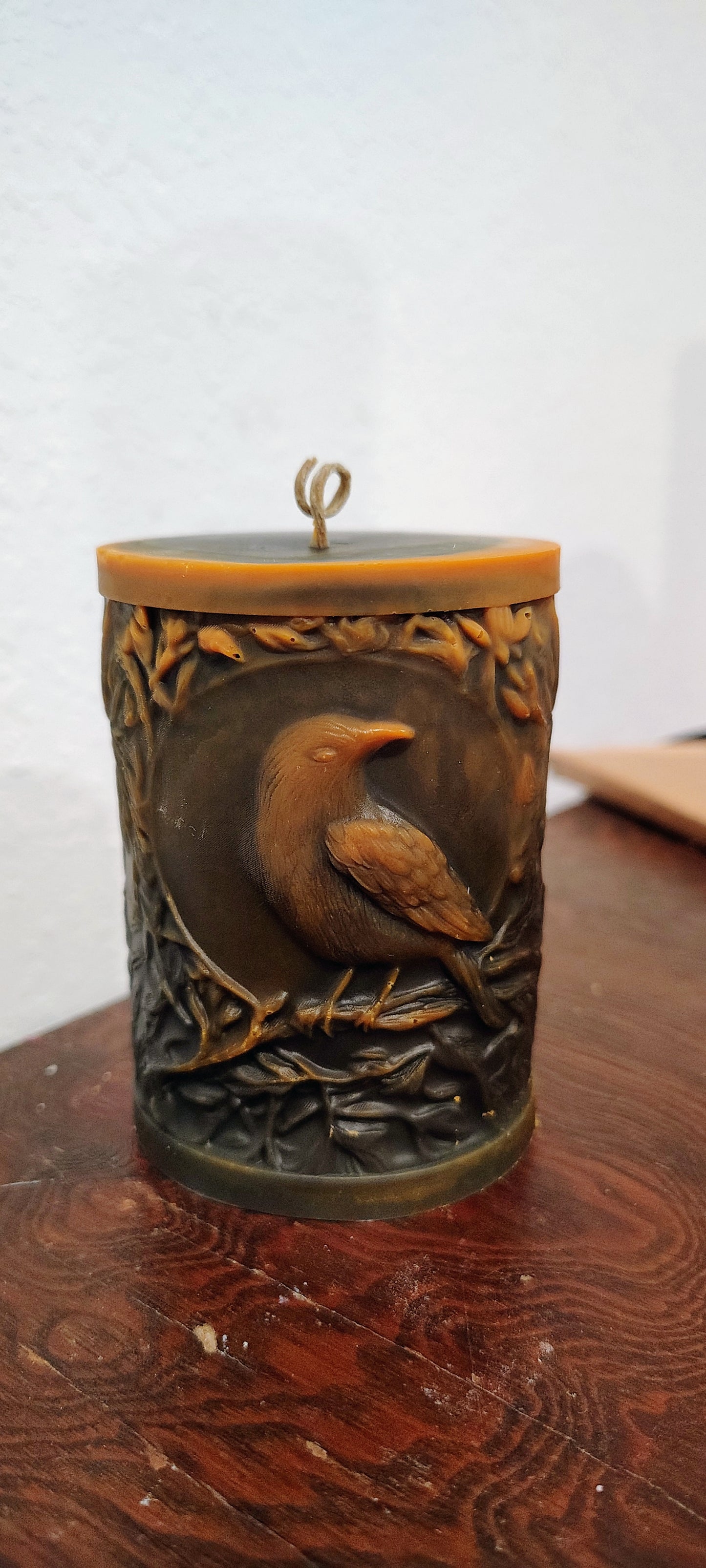 Black crow pillar candle with carved double‑sided crow design and customizable accent color, handmade in Sioux Falls, SD.