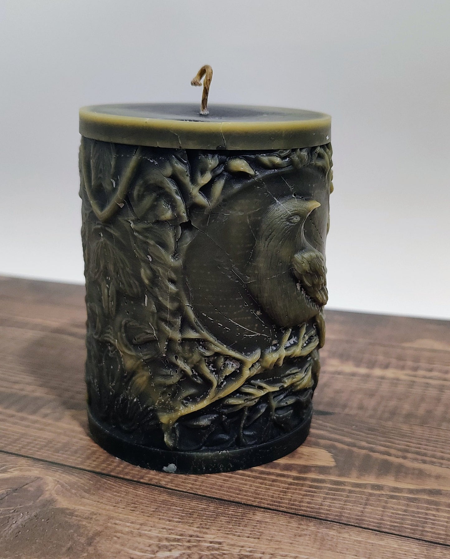 Black crow pillar candle with carved double‑sided crow design and customizable accent color, handmade in Sioux Falls, SD.