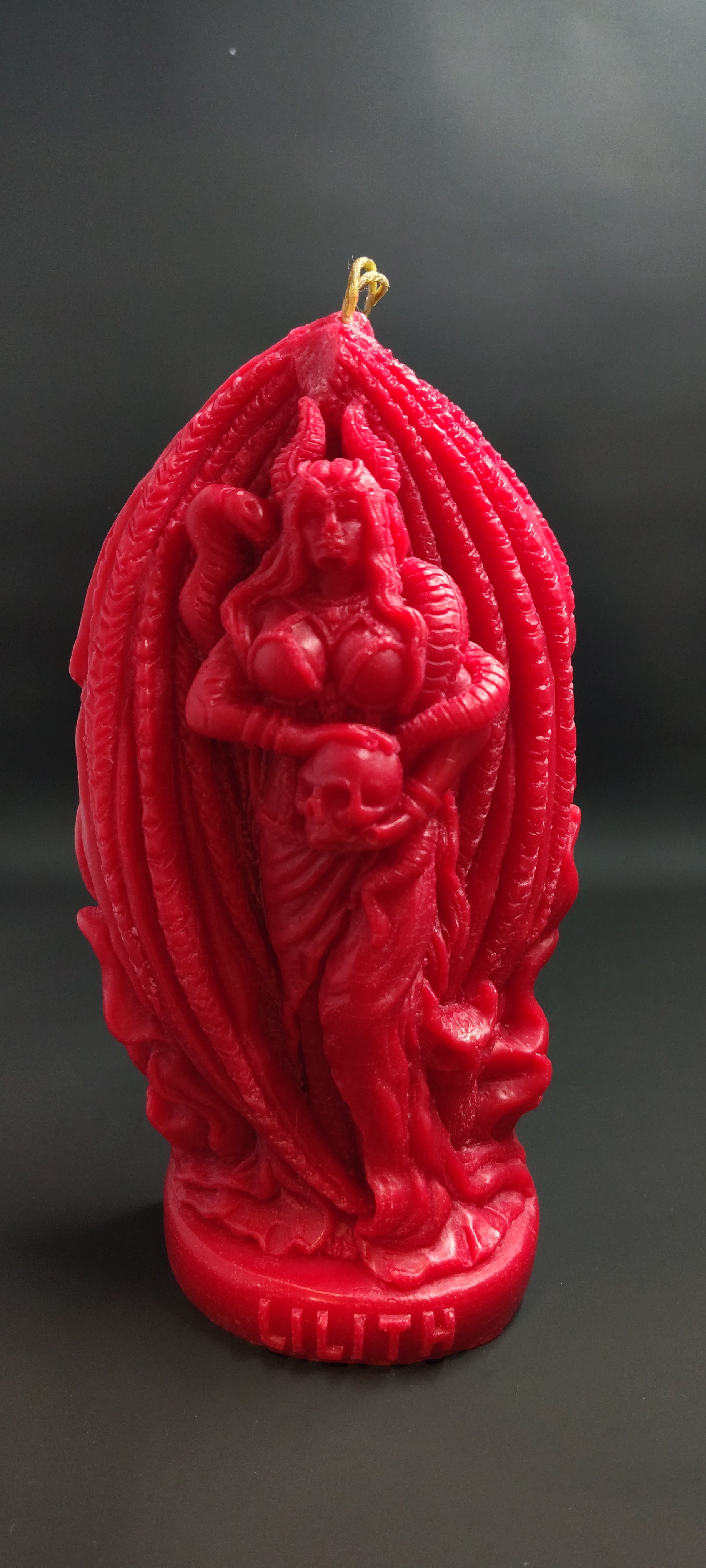 Red decorative Lilith candle with intricate designs on a black background